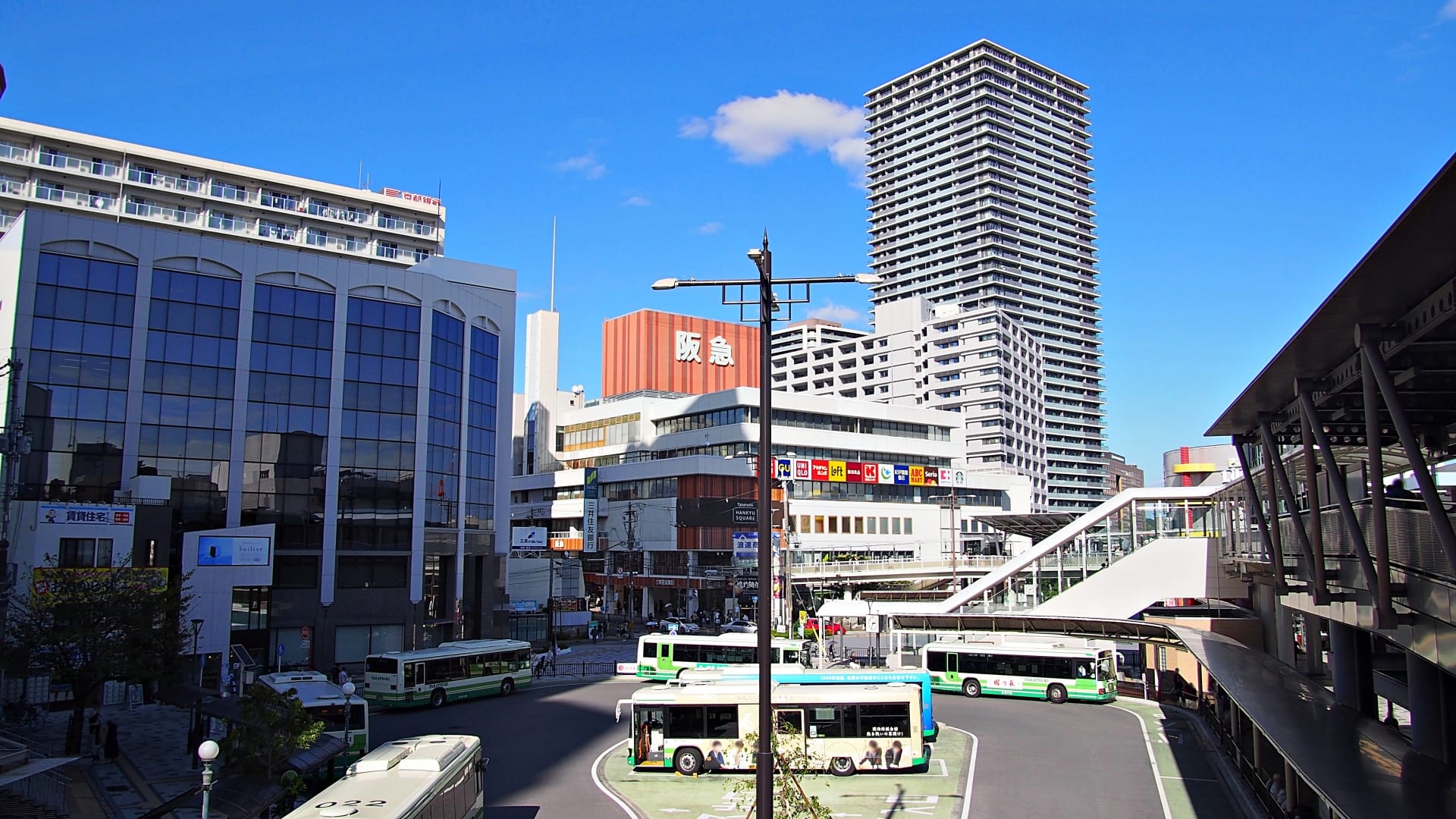 賑やかな高月市街地のバス停。高層ビルに囲まれ、澄み切った青空が広がる美しい風景です。.