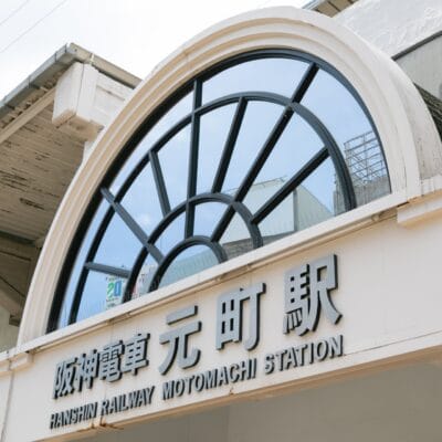 阪神電車元町駅の入り口には、駅名が日本語と英語で表示されている大きな半円形の窓があります。.