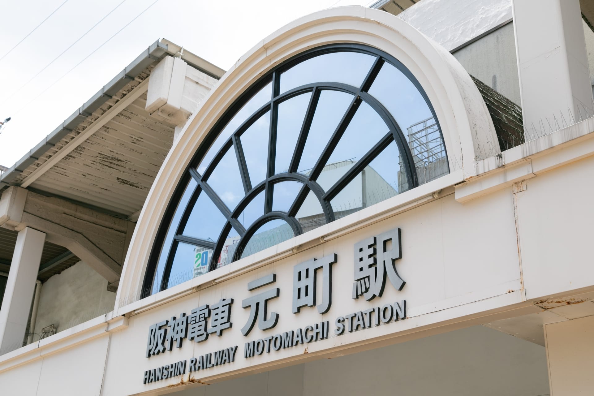 阪神電車元町駅の入り口には、駅名が日本語と英語で表示されている大きな半円形の窓があります。.