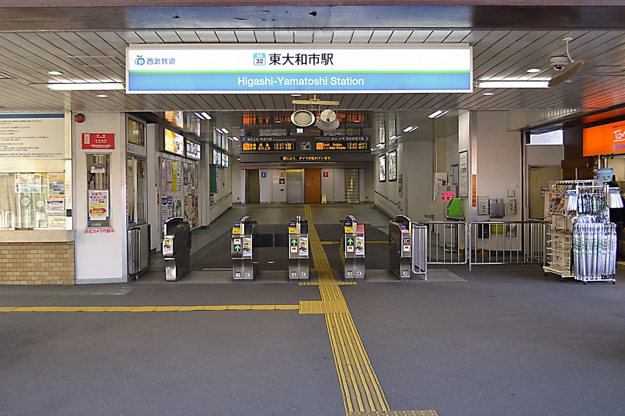 東大和市の東大和市駅の入口には、複数の改札口、標識、その上にある照明付きの出発案内板があり、韓国語教室のマンツーマン環境に見られる合理的な効率性を思い出させます。.