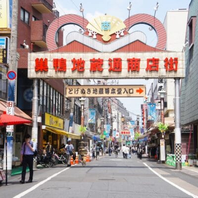 日本の巣鴨地区にあるにぎやかな通りには、頭上に大きな看板があり、その両側に複数の店が並んでいます。歩いたり自転車で通り過ぎたり、近くの韓国語教室マンツーマンのセッションに向かう人もいた。.