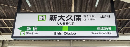 人気の韓国語教室マンマンクラスの近くのにぎやかな拠点である東京の新大久保の駅標識には、新宿と高田馬場への行き方が表示されており、駅コード JY16 が付いています。.