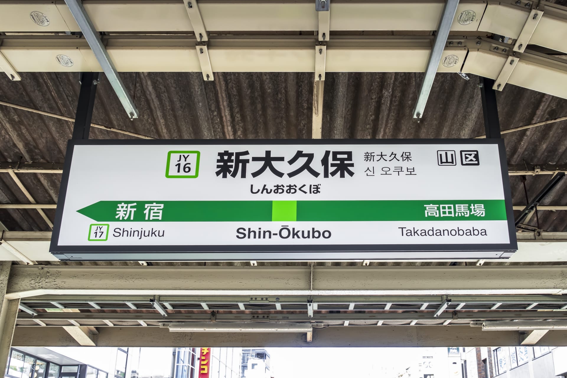 人気の韓国語教室マンマンクラスの近くのにぎやかな拠点である東京の新大久保の駅標識には、新宿と高田馬場への行き方が表示されており、駅コード JY16 が付いています。.