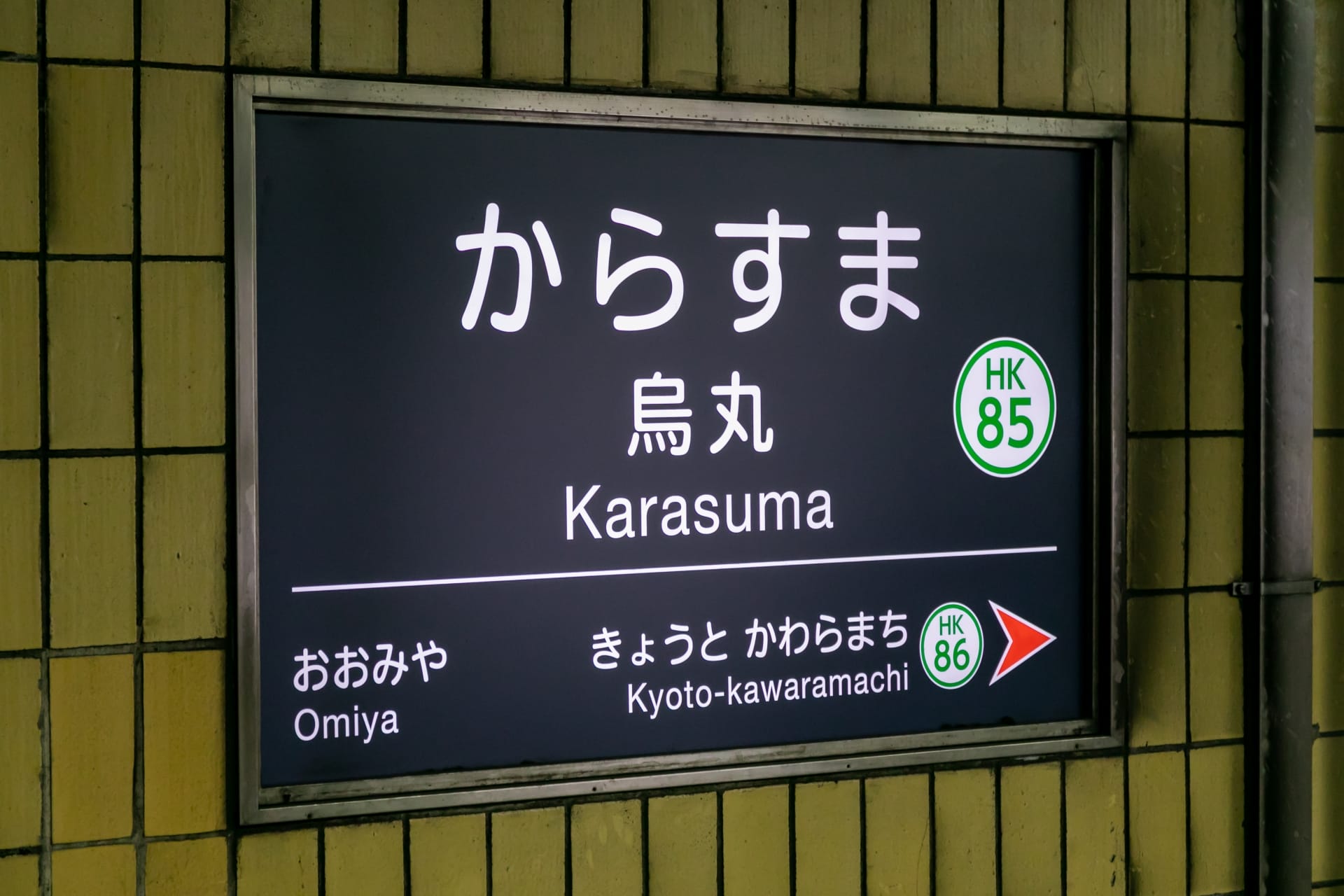地下鉄烏丸駅には、大宮と京都河原町への方向を示す標識があり、駅番号HK 85が明確に表示されています。.