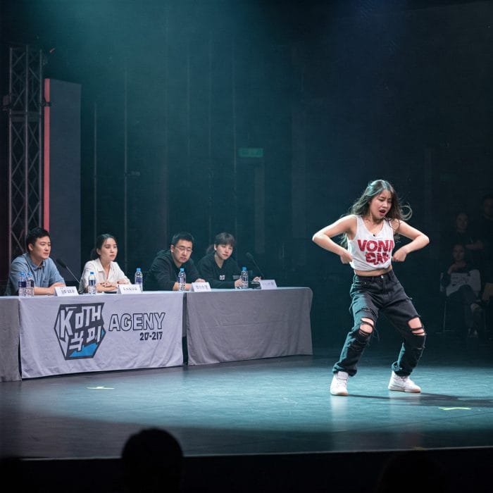 K-POP事務所のオーディション会場で審査員の前でパフォーマンスする志願者