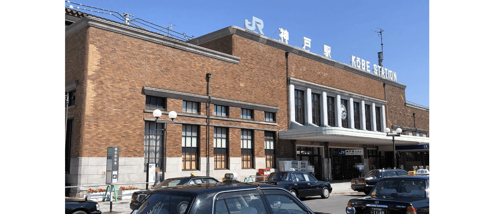 神戸駅のレンガ造りの駅舎には大きな窓があり、日本語と英語の看板が掲げられている。.