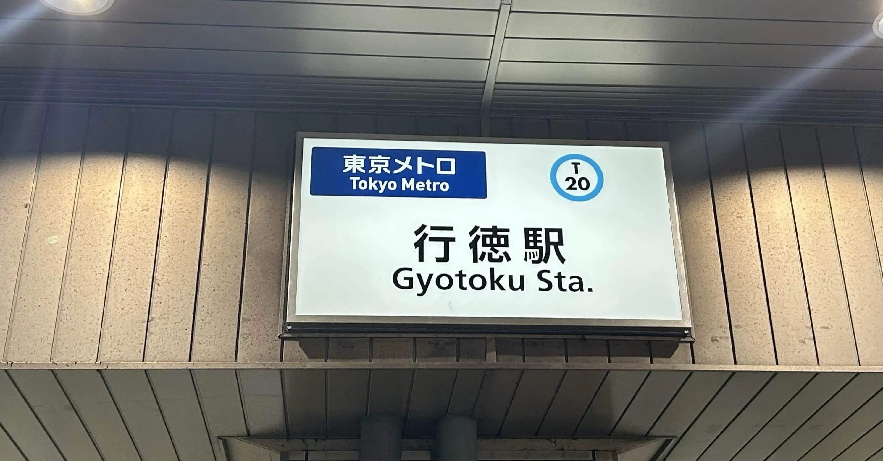 行徳駅（T20）の東京メトロの標識が、日本語と英語で壁に取り付けられている。.